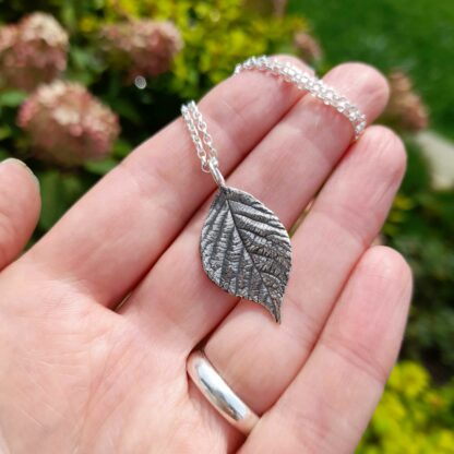 small-bramble-leaf-necklace-hand-background