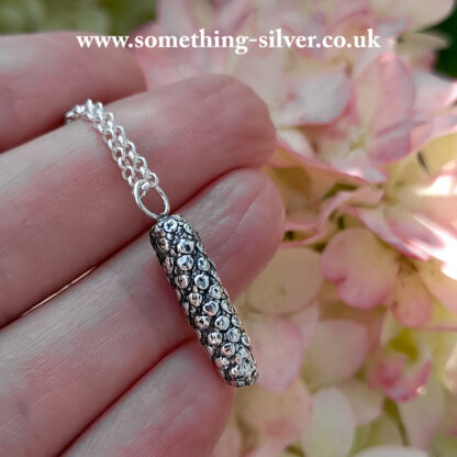 Sterling silver Alder flower pendant, on silver belcher chain. Held in hand with flower background