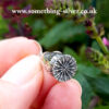 Sterling silver flanders poppy head pendant with silver belcher chain , held in hand, with natural background